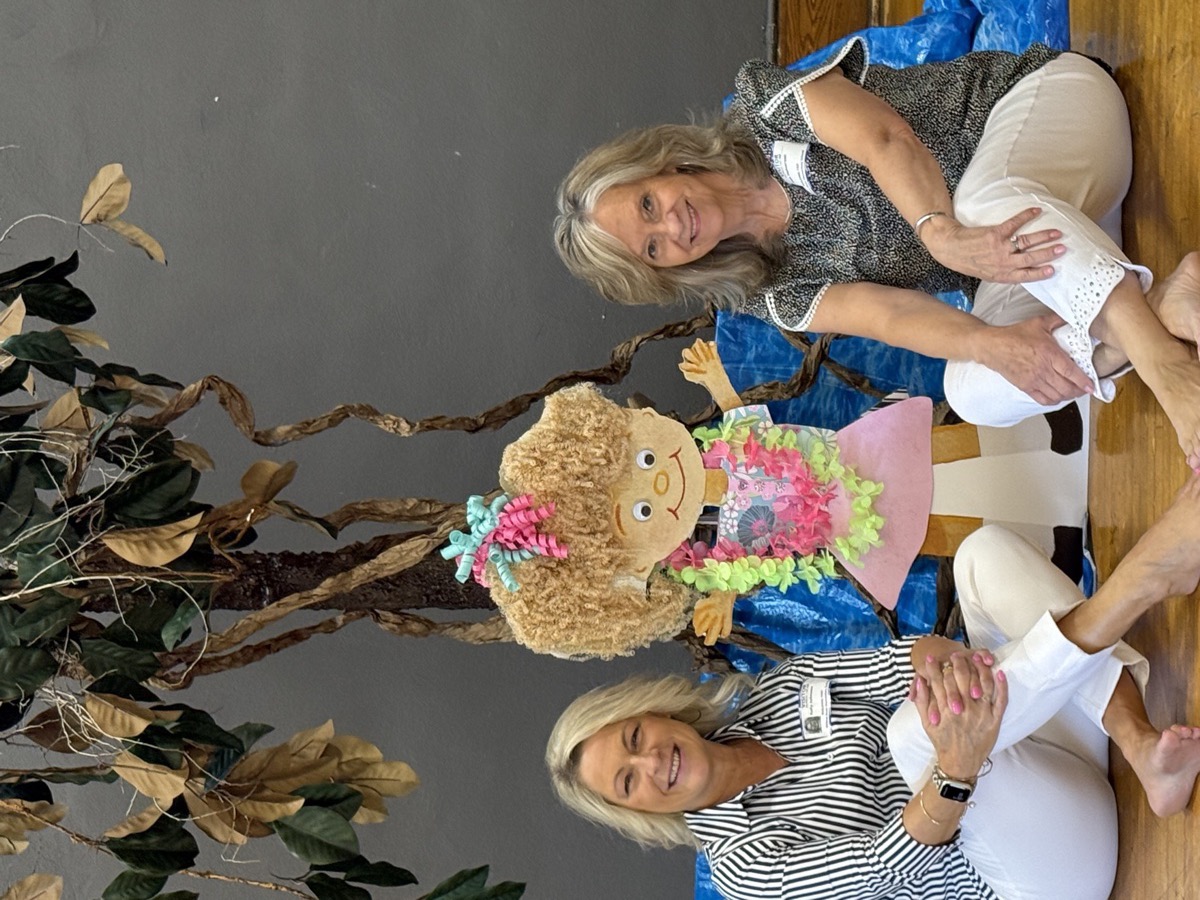 Kelly and Jean sitting on stage with the handmade Sandy paper doll character
